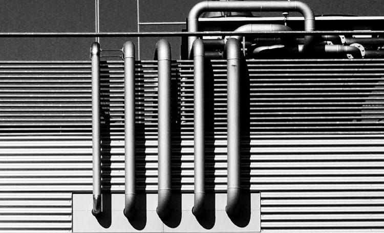 black and white industrial building exterior with exposed pipes