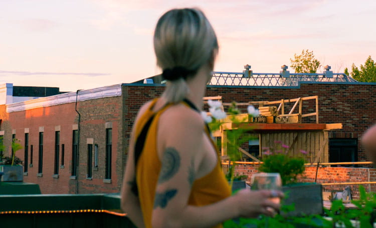 Woman with a glass in hand on rooftop at sunset