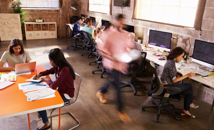 workers in coworking space blurred man walking past seated women